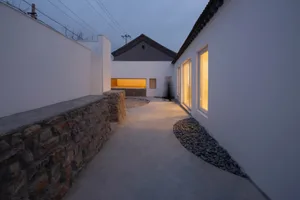 A contemporary residential exterior featuring concrete walls, stone accents, and a landscaped garden.