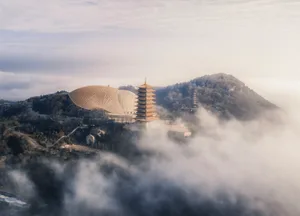The image depicts a modern architectural structure surrounded by clouds.
