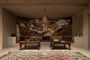 A modern living room featuring a large, painted mural on the wall, wooden furniture, and a patterned rug.