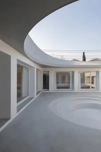 Modern minimalist residential interior featuring a circular concrete floor and large glass windows.