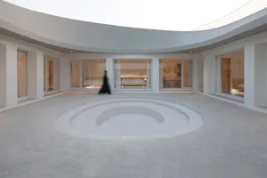 Circular minimalist interior space with concrete flooring and large windows.