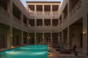 Traditional Arabic residential courtyard with a swimming pool surrounded by concrete walls and balconies.