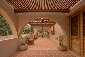 A serene indoor space with an arched walkway, tiled floor, and natural light pouring in through the open doors.
