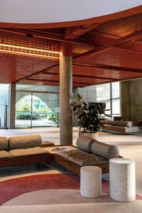 An industrial-style lobby with concrete columns, metal ceiling, and seating areas.
