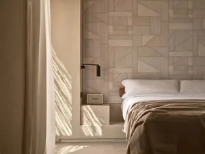 Minimalist bedroom with geometric pattern wallpaper, soft lighting, and fabric bedding.