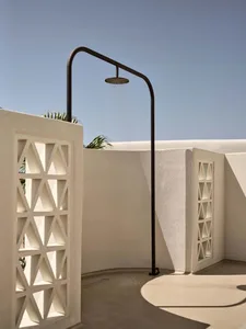 A minimalist outdoor shower with a metal frame, against a clear blue sky.