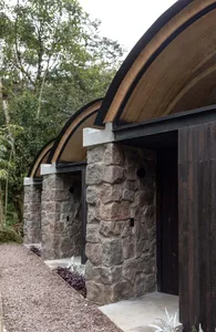 Modern, minimalist residential homes with stone exteriors surrounded by lush greenery.