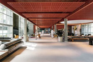 A spacious and modern lobby with concrete flooring and a grid-patterned ceiling.