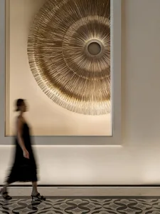A modern lobby features a metallic-textured circular artwork hanging on the wall.