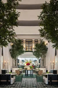 Modern lobby filled with greenery, tables, and seating areas.