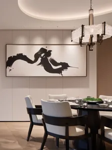 Modern minimalist dining room with wooden table, fabric upholstered chairs, and abstract black and white wall art.