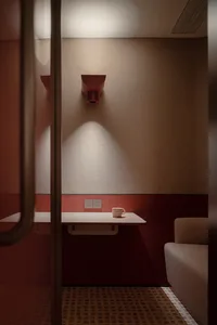 A minimalist waiting area with a single mug on a table against a neutral-toned wall and red accents.