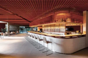 A modern restaurant bar with metallic and wooden features, showcasing contemporary design elements.
