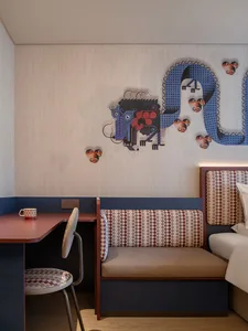 A modern room decorated with fabric elements, featuring a desk, chair, sofa, and unique wall art.