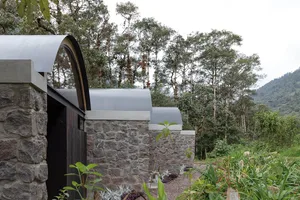 A modern house with stone walls and a curved roof.