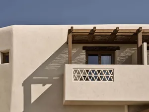 Modern residential architecture featuring sandstone walls and wooden pergola.