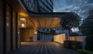 A modern hotel entrance with concrete flooring and glass structure.