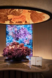 A modern reception desk with a marble top and crystal elements, featuring a flower arrangement and an information folder.