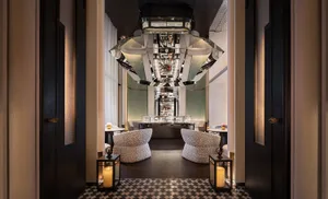 Modern restaurant interior with a glass chandelier, wooden tables, and fabric chairs