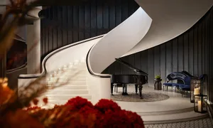 A luxurious white marble living room with a grand piano, floral decor, and elegant seating arrangements.