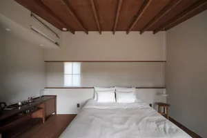 A minimalist bedroom with a bed, white bedding, and a wooden table.