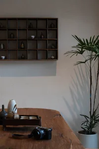 A decorative container made of wood sitting on a wooden table with other objects around it.