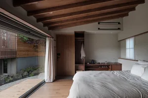 A minimalist bedroom with okiriko wood flooring and a view of a garden.