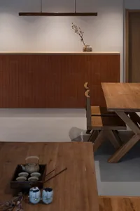 A minimalist dining room featuring wooden furniture and a wooden table with tea set and chopsticks.