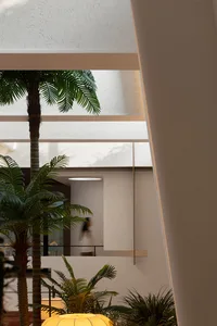 A minimalist indoor living space featuring concrete pillars and lush green plants.