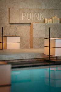 A minimalist spa setting with stone walls, lit candles, and a water feature.