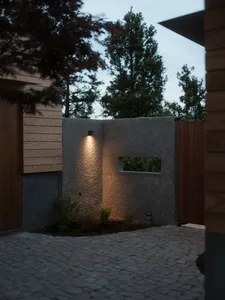 A modern concrete wall illuminated at night with a light fixture casting a warm glow.