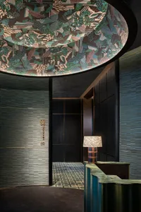 A contemporary lobby with a visually striking ceiling design, featuring a mix of materials and dark wood finishes.