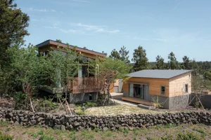 Modern residential house featuring wooden exterior, glass windows, and concrete base.