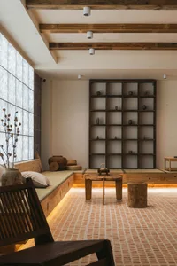 A modern living room with a wooden floor, low wooden furniture, and a large window.