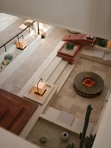 An aerial view of a modern living space with a concrete floor, a cozy fireplace, and various seating arrangements.