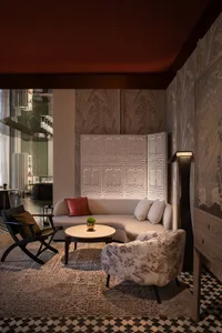 A modern living room with a white sofa, round coffee table, and patterned rug.