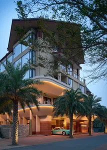 Modern hotel exterior featuring concrete, glass, and palm trees.