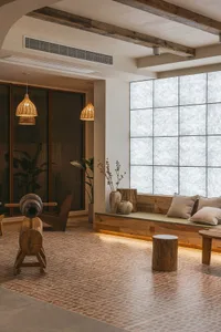 A cozy living room with a wooden floor, concrete accents, and comfortable seating arrangements, featuring rustic lighting fix