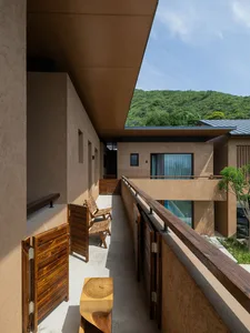 A contemporary residential balcony featuring wood furniture, a tree, and a mountain view.