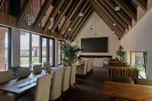 Industrial restaurant interior featuring concrete walls, wooden tables, and glass windows.