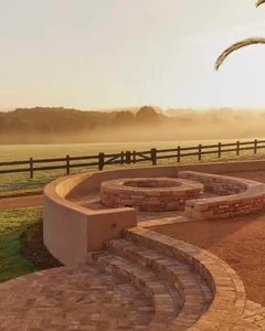 A landscape featuring a brick stone fire pit surrounded by a circular seating area.