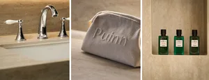 Close-up of a modern bathroom sink with metallic fixtures, a grey fabric pouch with the word 'Puuh', and green bottles of bat