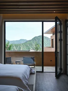Modern bedroom with a glass sliding door overlooking mountains.