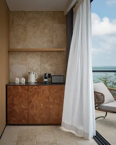 A modern interior balcony featuring a wooden cabinet with geometric patterns, a white coffee maker, a toaster, and a speaker.