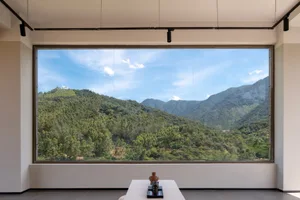 A minimalist interior design featuring large glass windows showcasing a scenic mountain view.