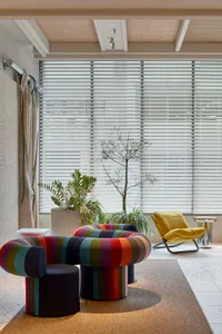 A contemporary living room featuring a colorful, multicolored sofa under a large window with blinds.