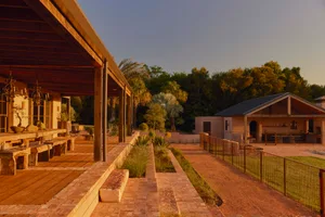 A modern residential landscape featuring brick pavers, stone paths, and a mix of wood and metal elements.