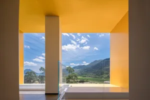 Modern window overlooking lush mountains and clear blue sky