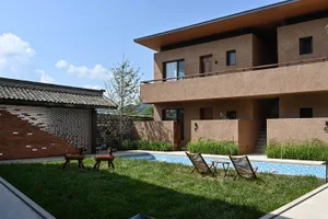 Modern residential exterior featuring a backyard with a swimming pool, concrete surfaces, and grass