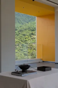 A modern interior design featuring a glass window overlooking natural greenery.